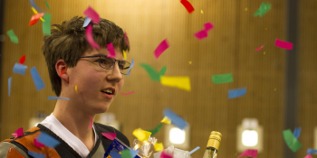 Bilde av en smilende Thomas Peelen mens han holder en kurv full av premier og konfettien regner rundt