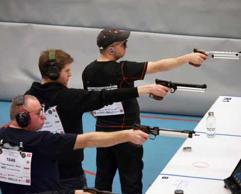 Bilde av tre pistolskyttere på rekke med løftet våpen, klare for skudd.